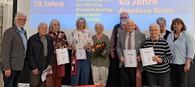 Geehrte Jubilarinnen und Jubilare mit ihren Urkunden auf der Bühne